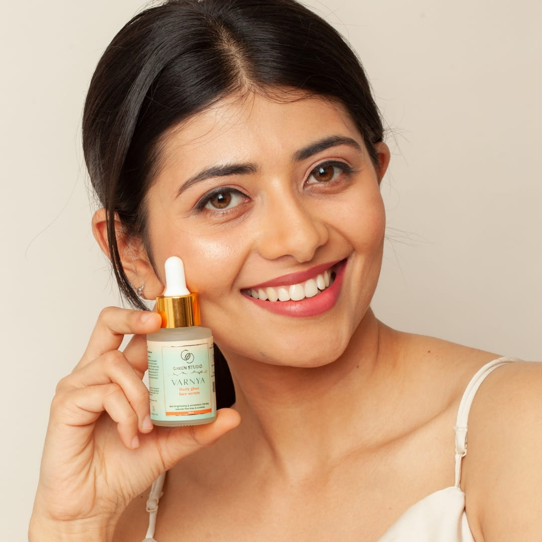 A young beautiful lady with clear skin holding the Daily Glow Serum from Green Studio Ayurveda